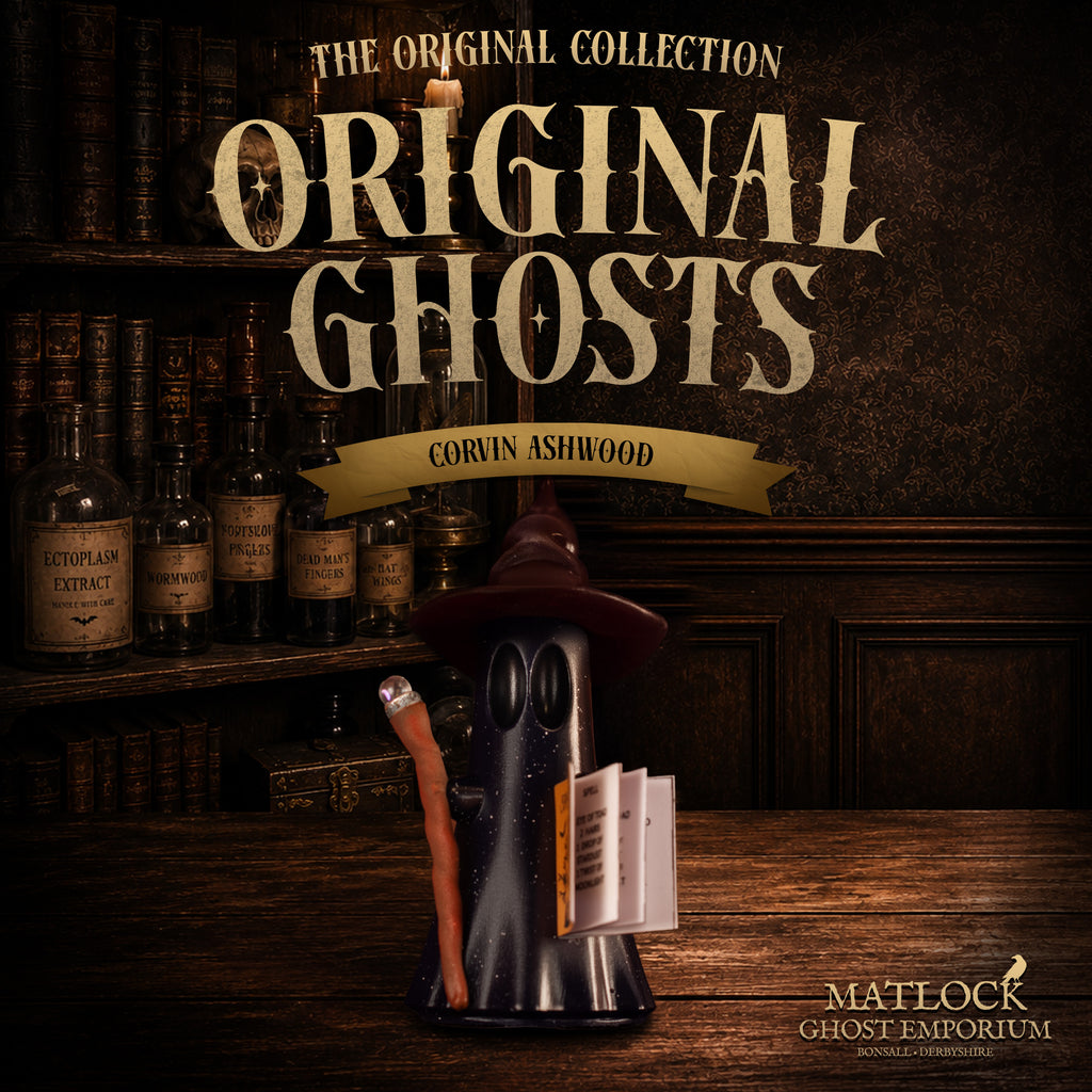 A Halloween-themed product display featuring a ghost-shaped candle holder wearing a witch hat and holding a broom and book, set on a wooden table in front of a dark bookshelf background. Large text reads 'The Original Collection Original Ghosts' with 'Corvin Ashwood' and 'Matlock Ghost Emporium' visible.